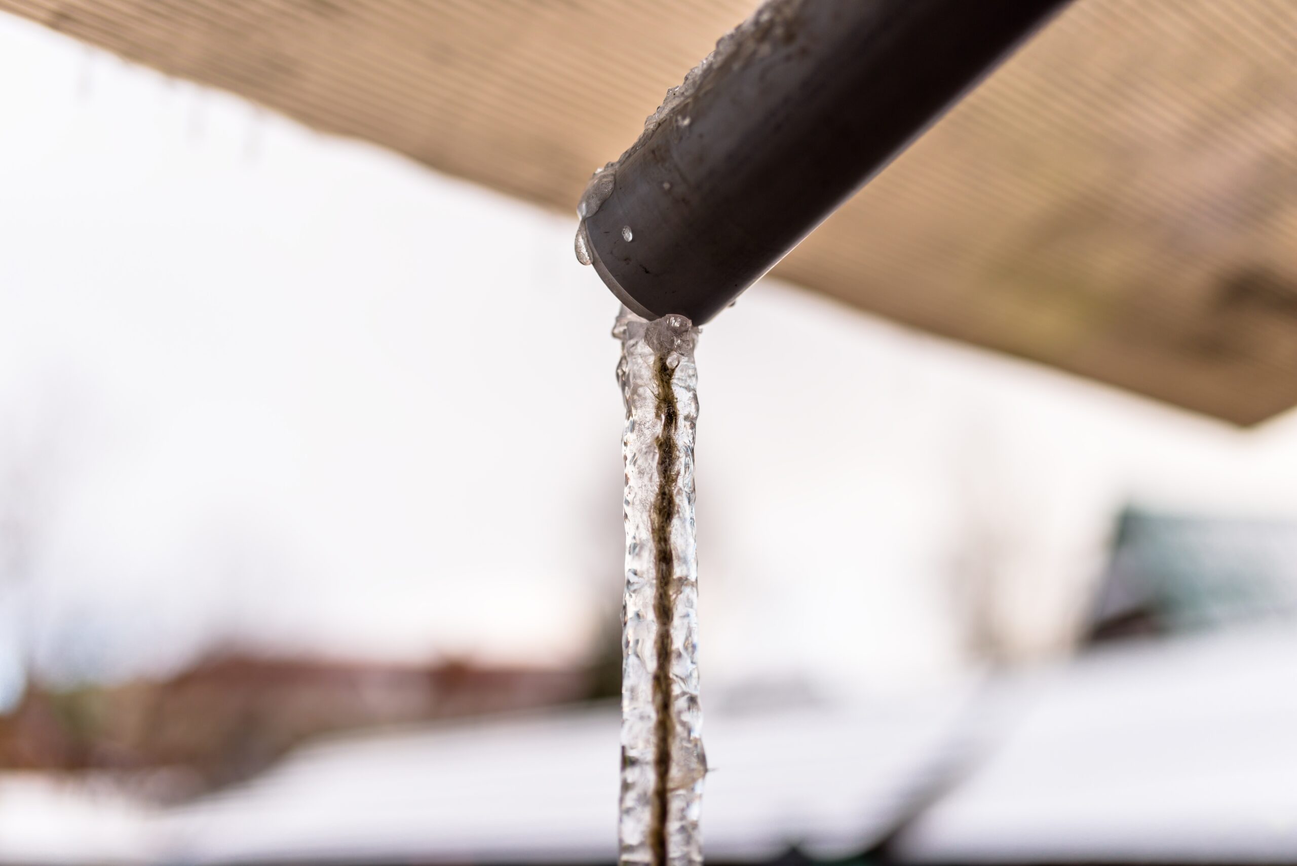Frozen water flowing from the roof through a pipe
